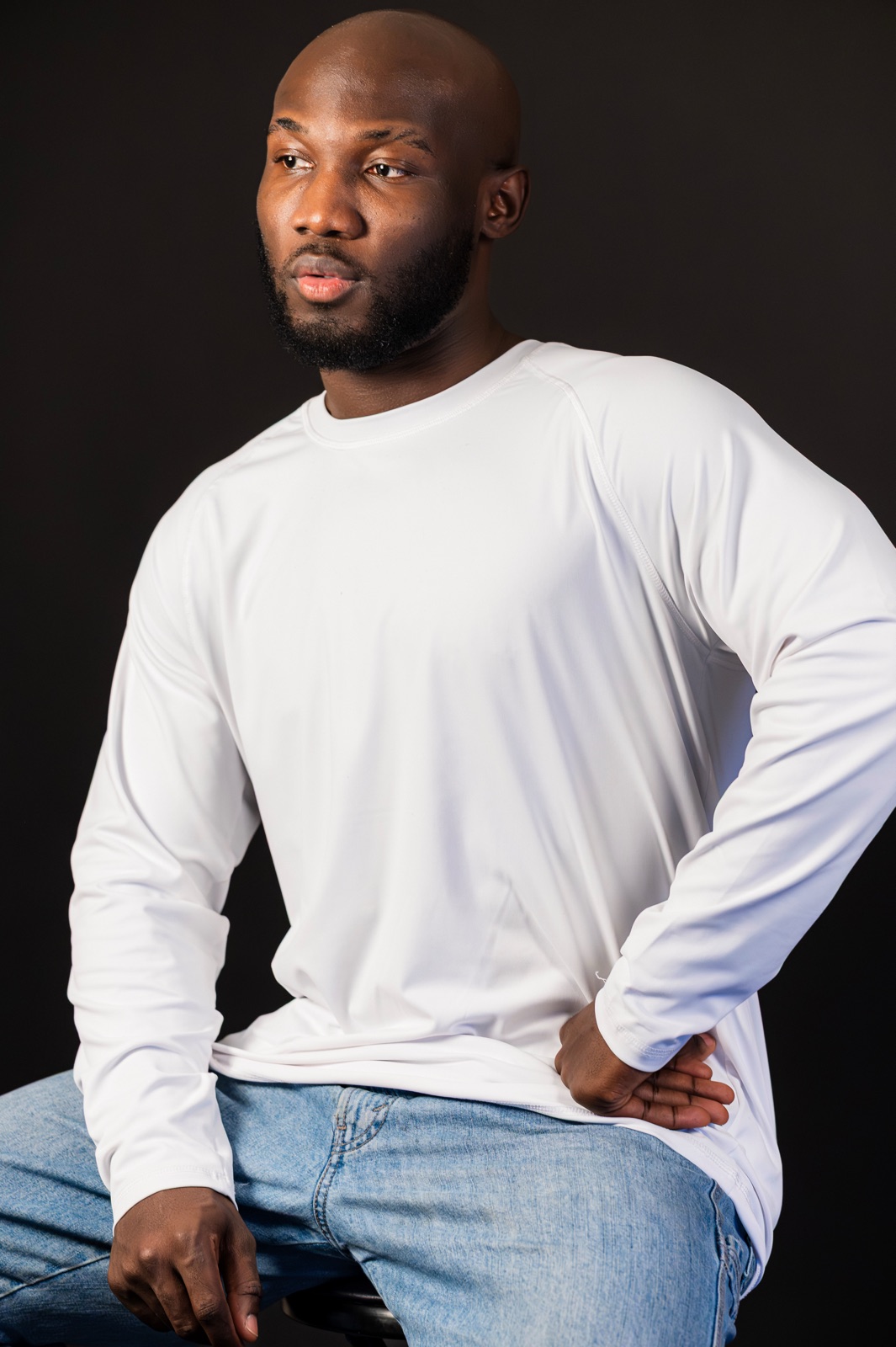 Bald studio portrait, white long-sleeve, dark backdrop