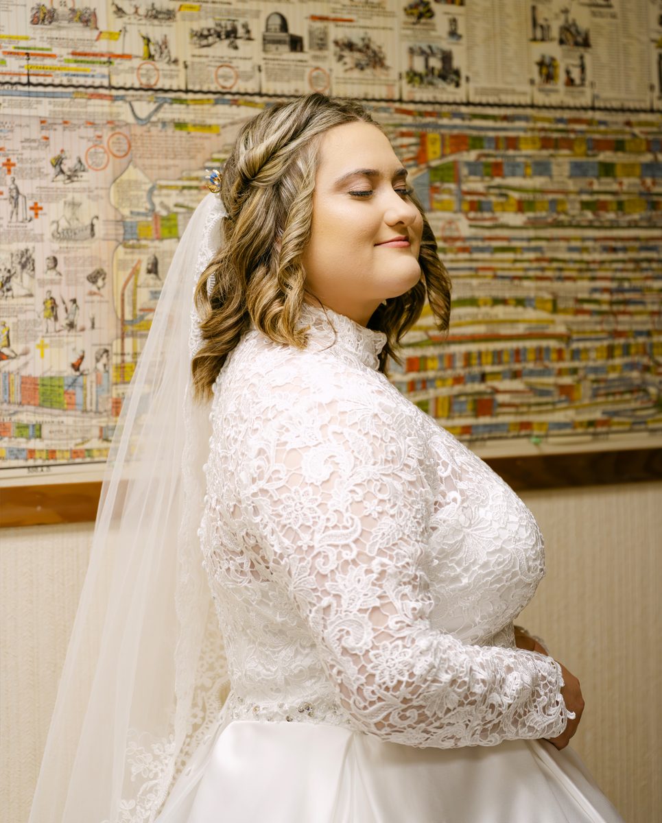 Bride in lace, profile, before a painted mural