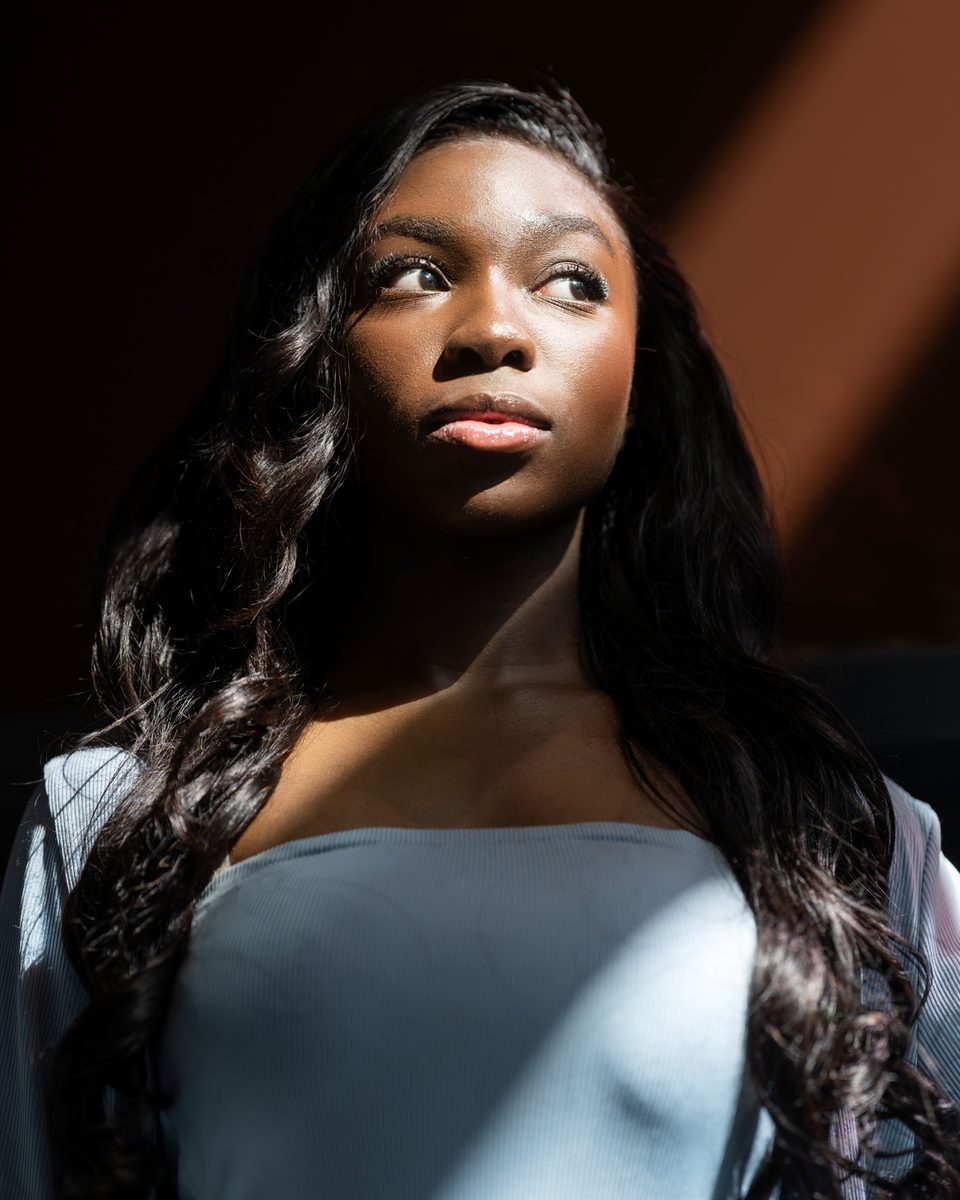 Face in hard window light, looking up, powder-blue gown