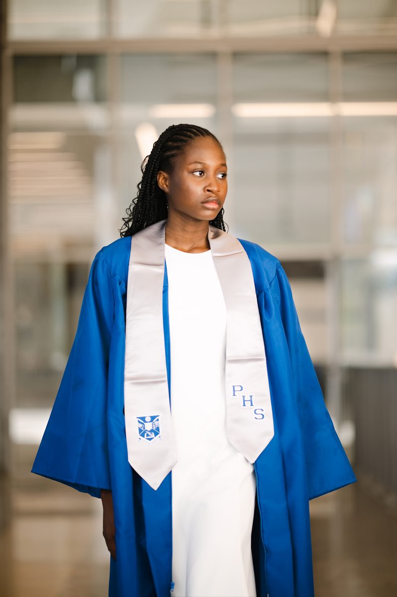 Graduate in a blue gown in a bright school atrium
