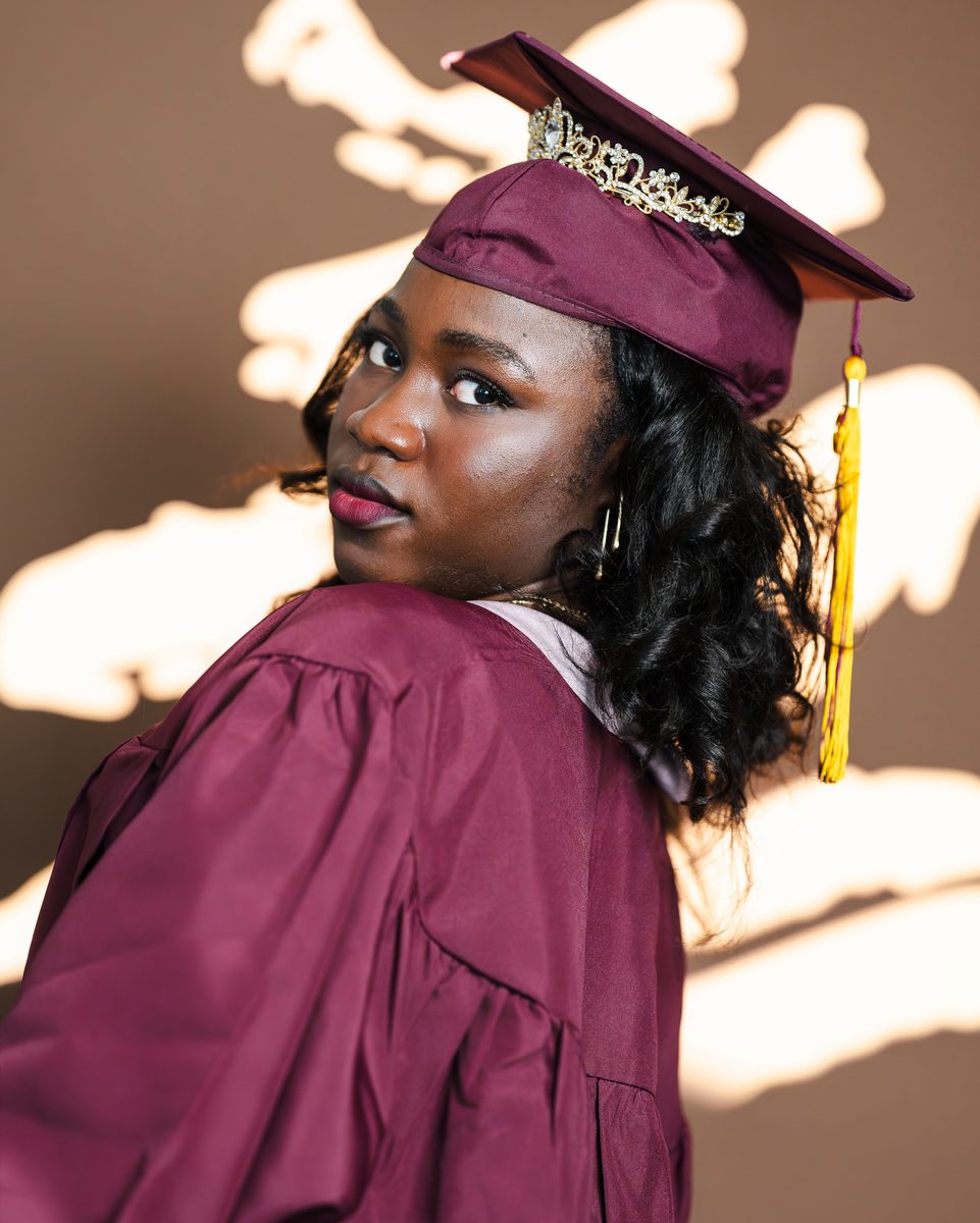 Maroon gown and cap, looking back over her shoulder