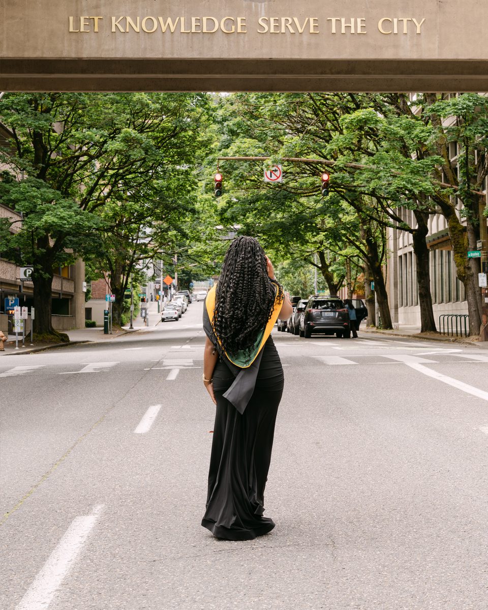 Graduate walking away down a tree-lined Portland street