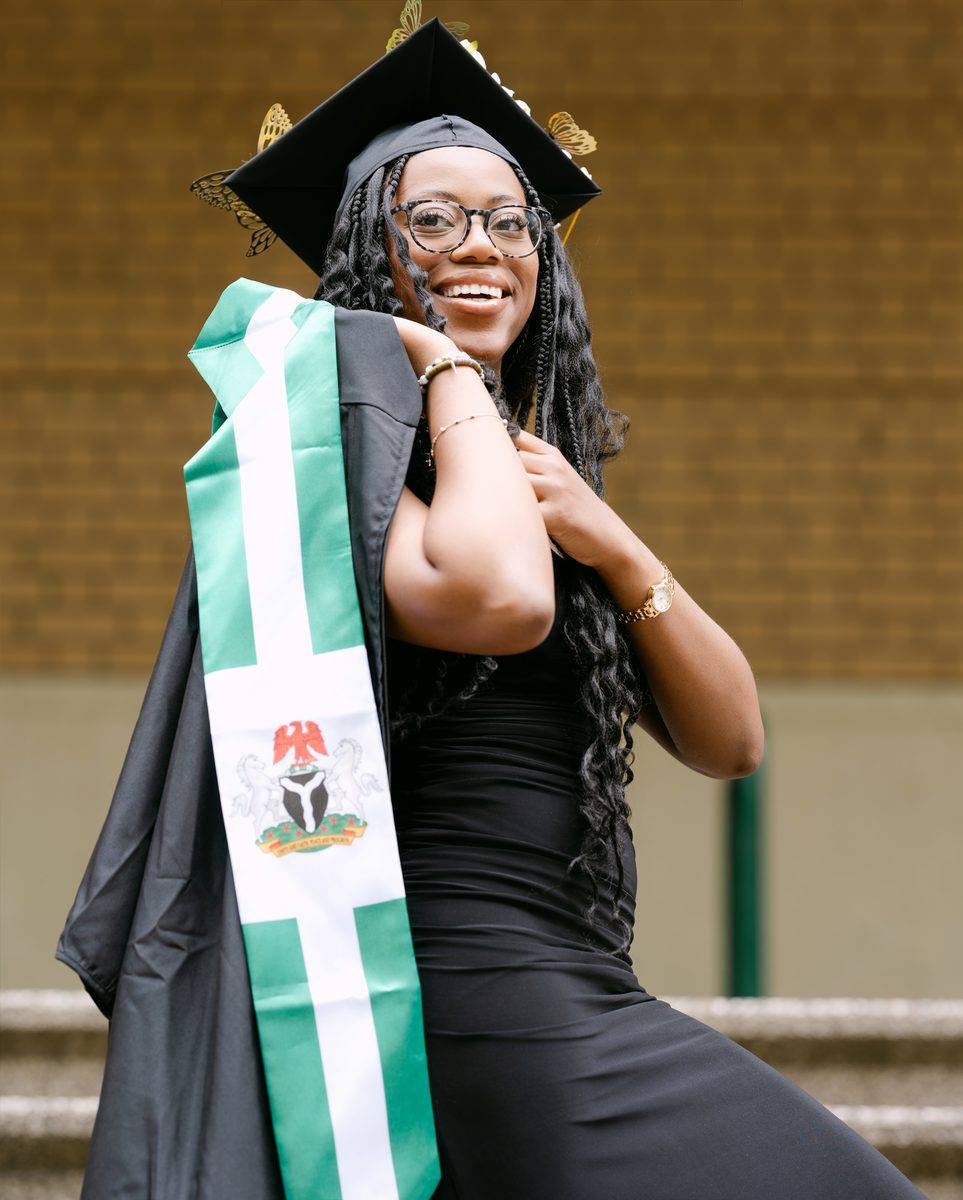 Graduate with a Nigerian-flag stole on stone steps