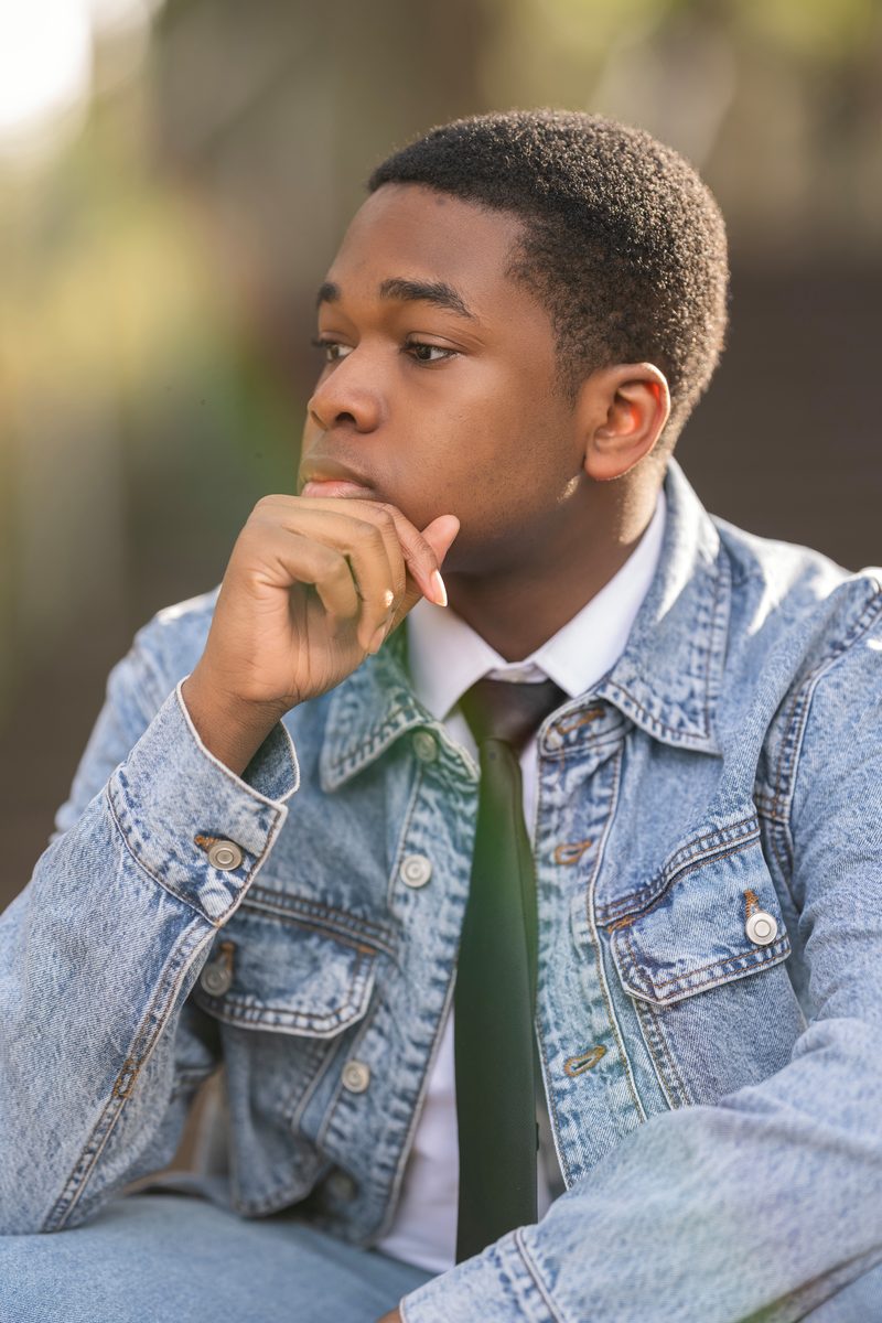 Denim jacket and tie, hand at his chin