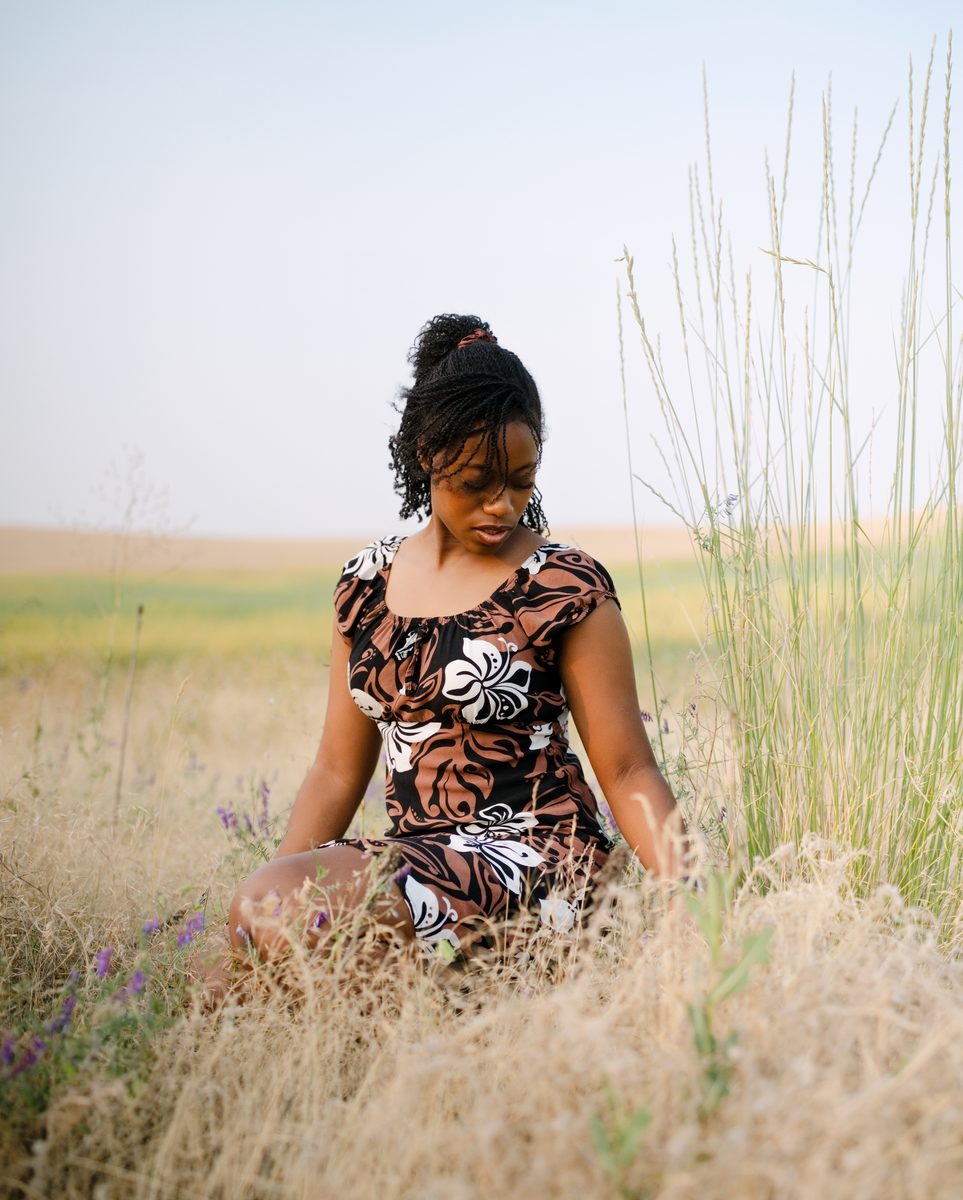 Seated in tall grass in a floral dress