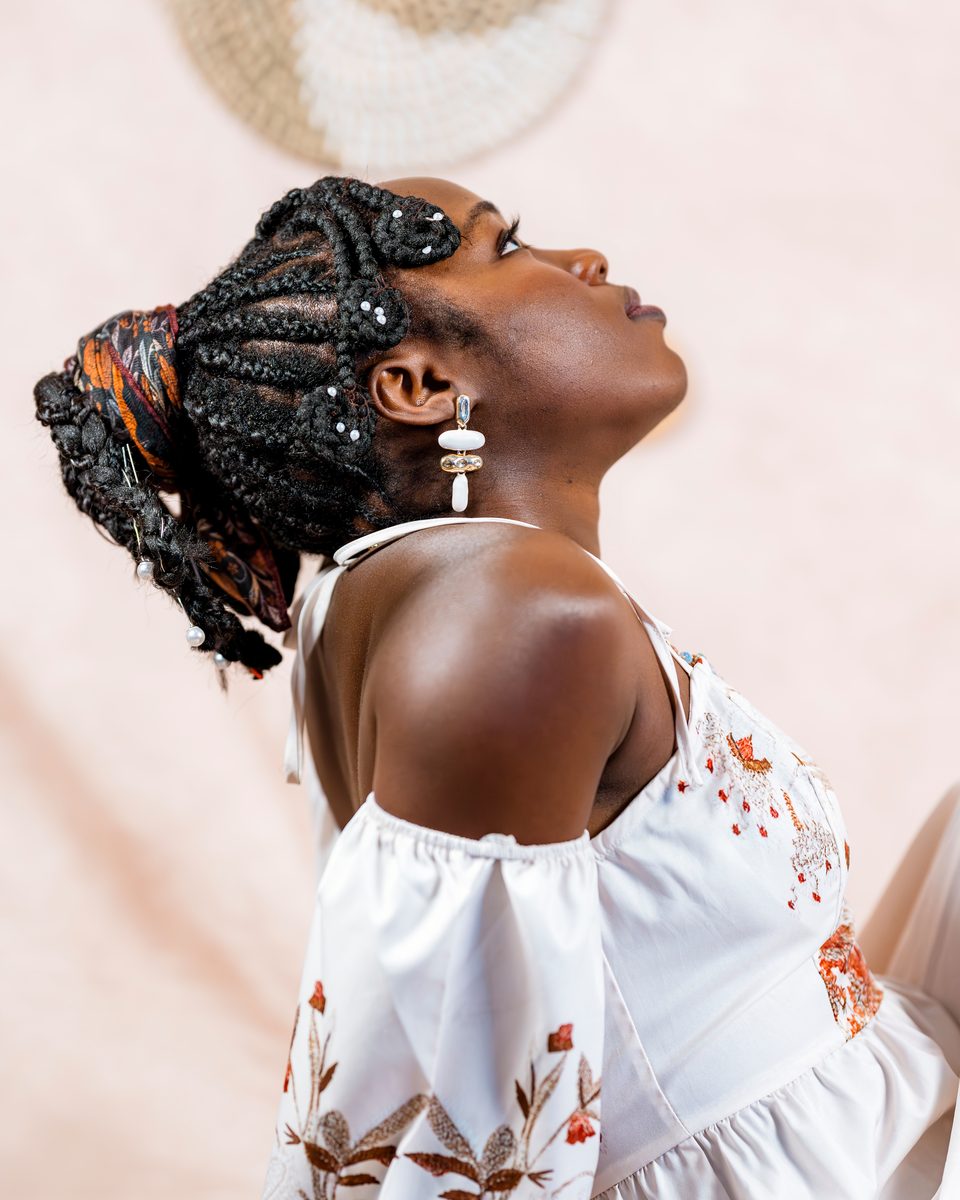 Profile with beaded braids and pearl earrings, eyes closed