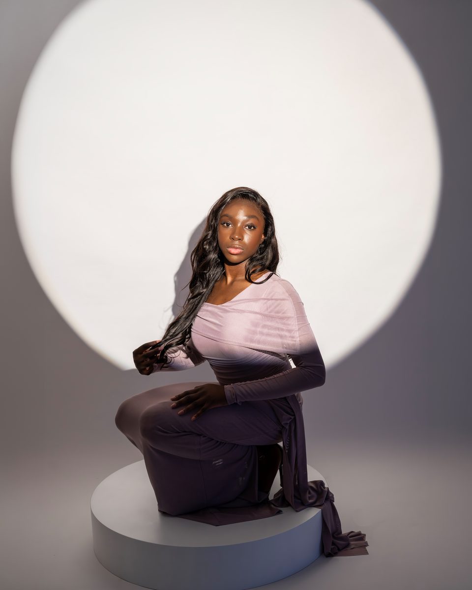 Lilac gown, kneeling on a plinth in front of a white circle