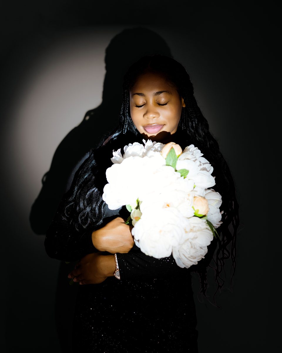 Holding white peonies in a pool of light on black