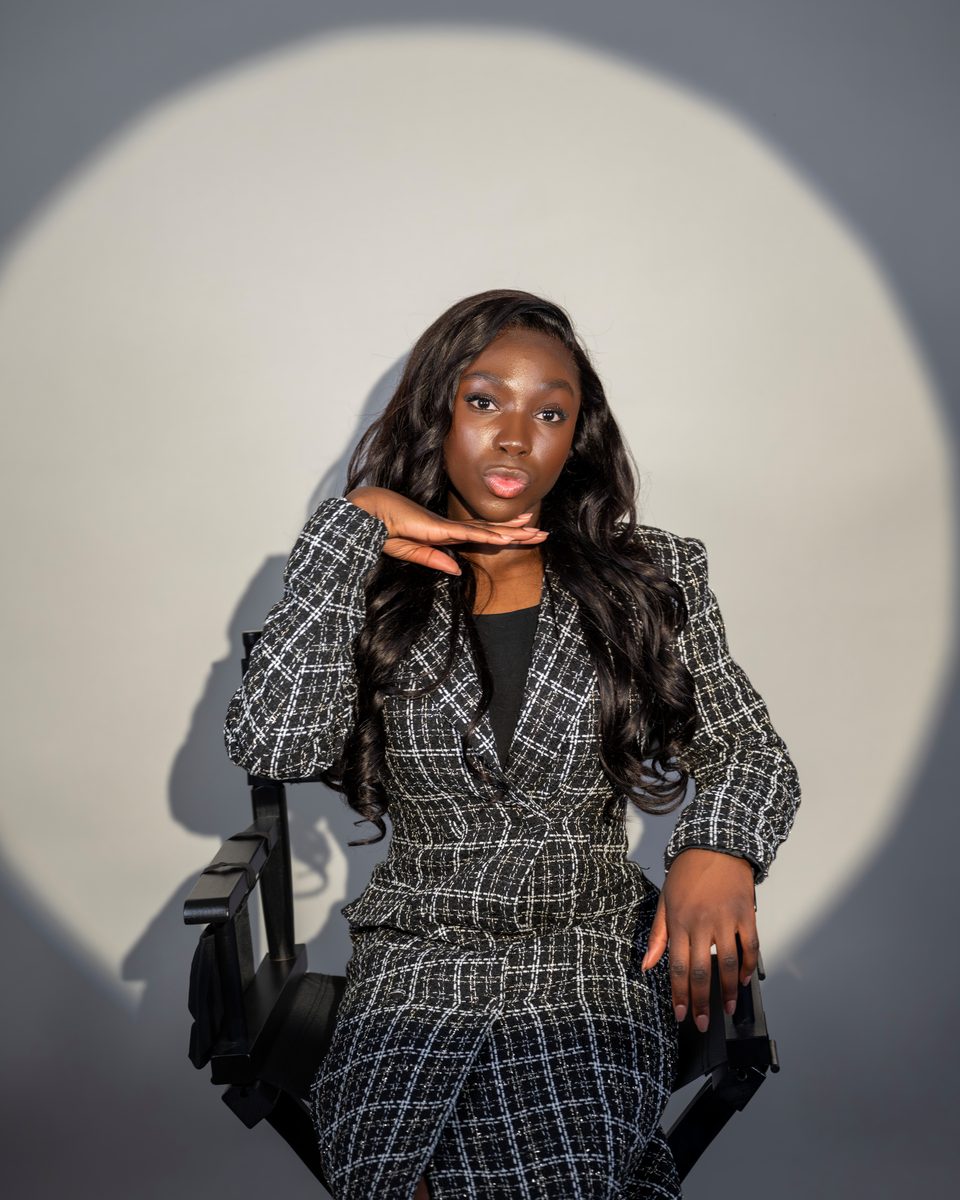 Tweed suit in a director's chair before a white circle