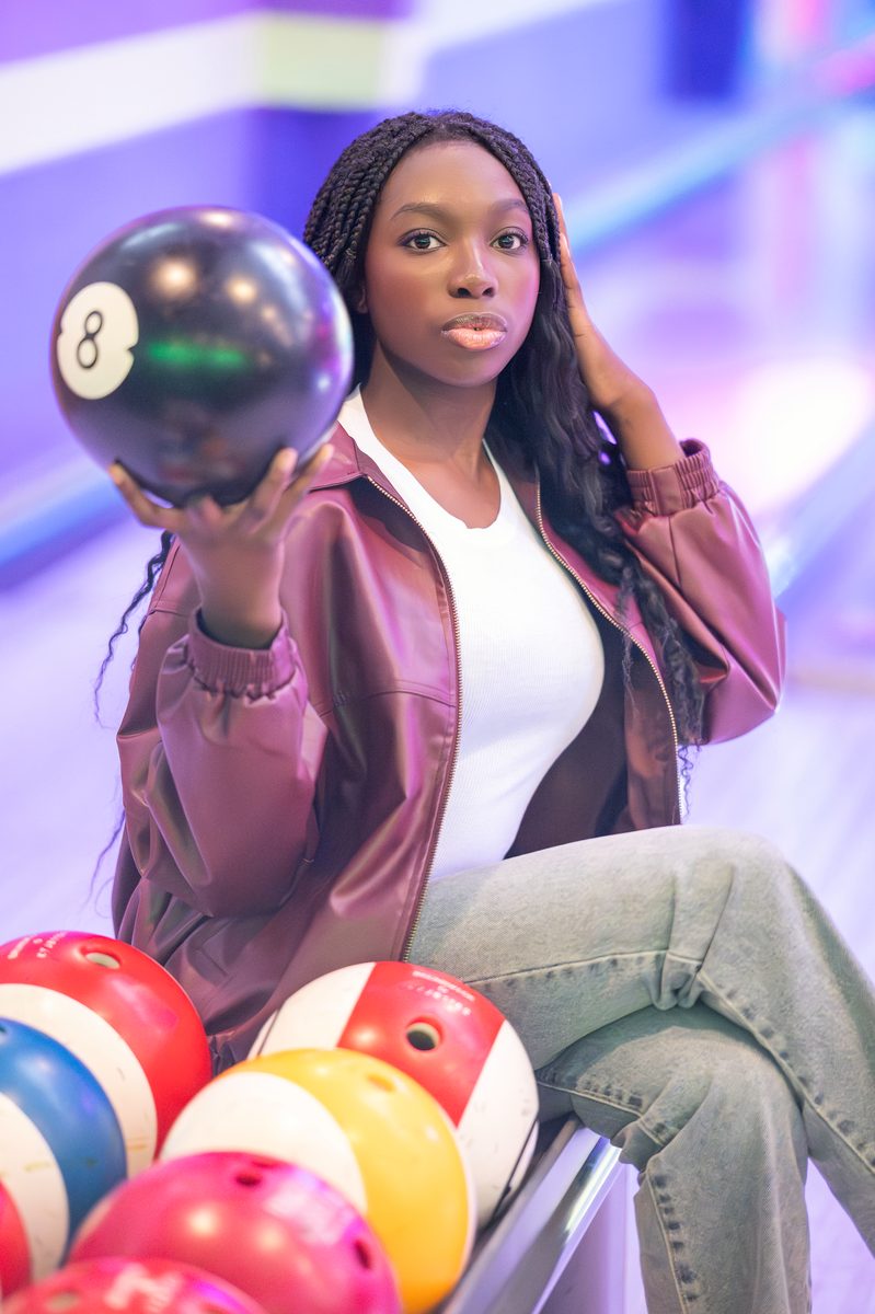 Holding an eight ball above a rack of bowling balls