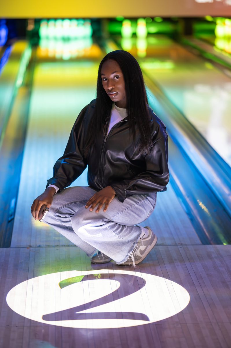 Crouched on a bowling lane under neon light