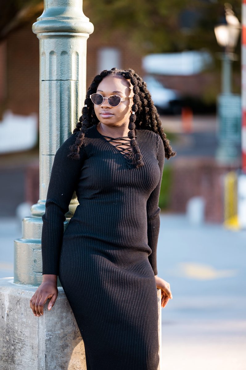 Black dress and sunglasses beside a green lamppost